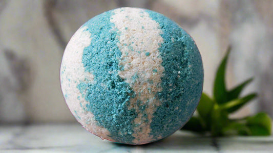 Green and white striped bath bomb on a surface with a blurred background