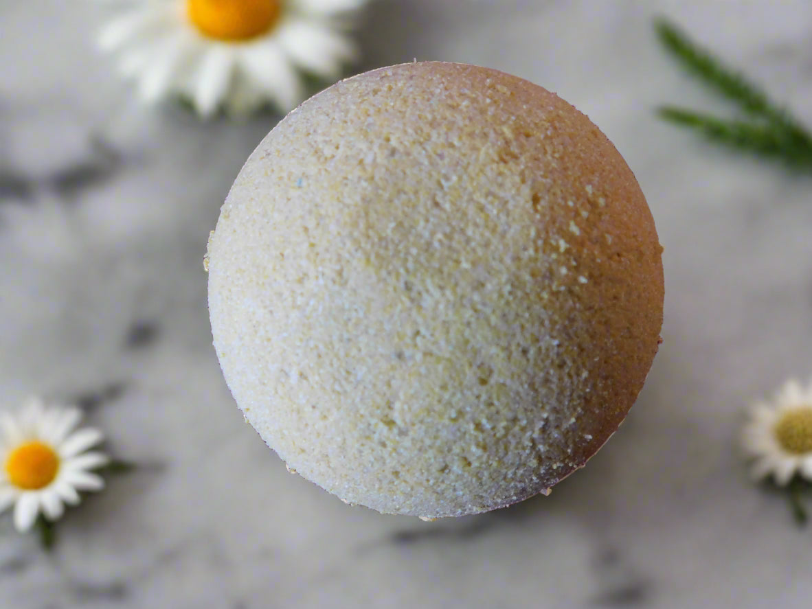 yellow chamomile bath bomb round with chamomile flowers all over the marble counter