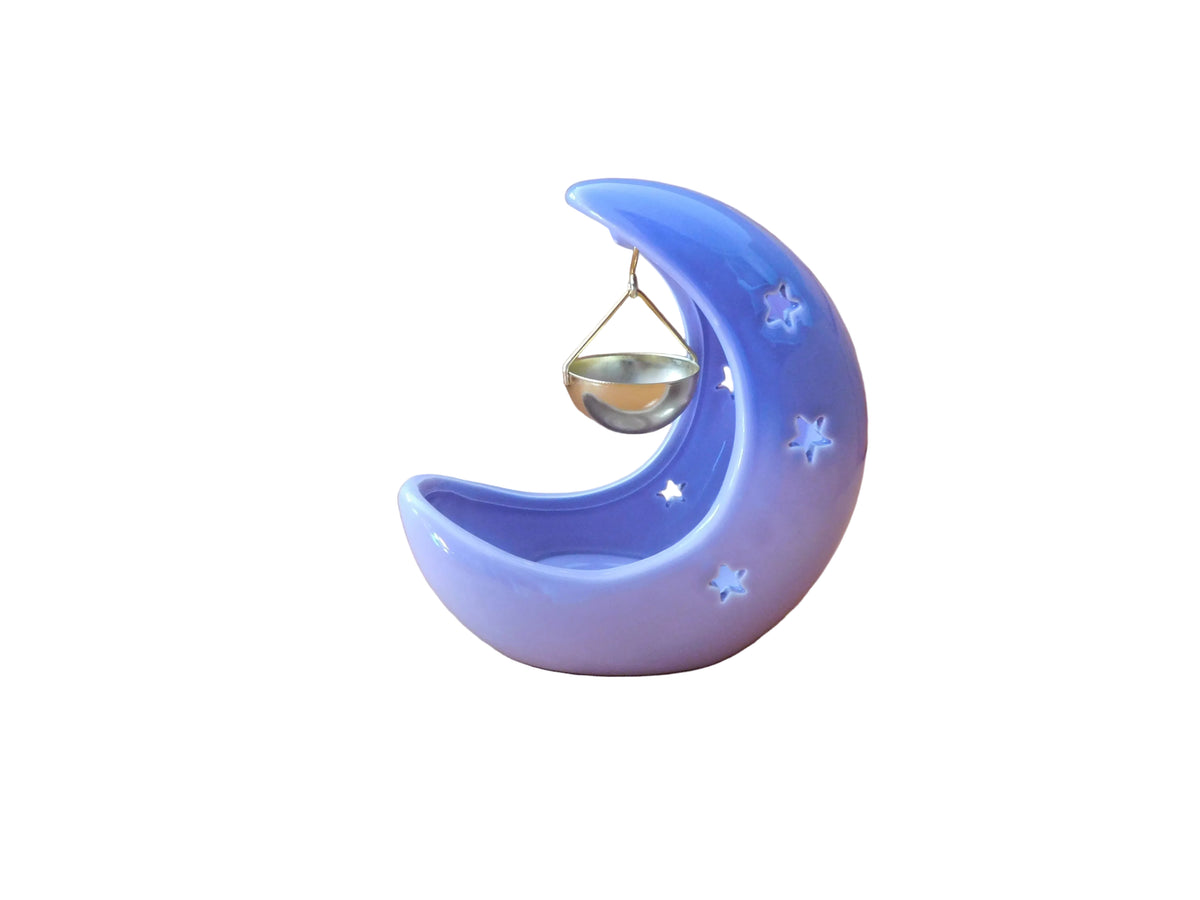 A pastel purple crescent moon-shaped decorative candle holder with star cuts outs and a small hanging gold bowl