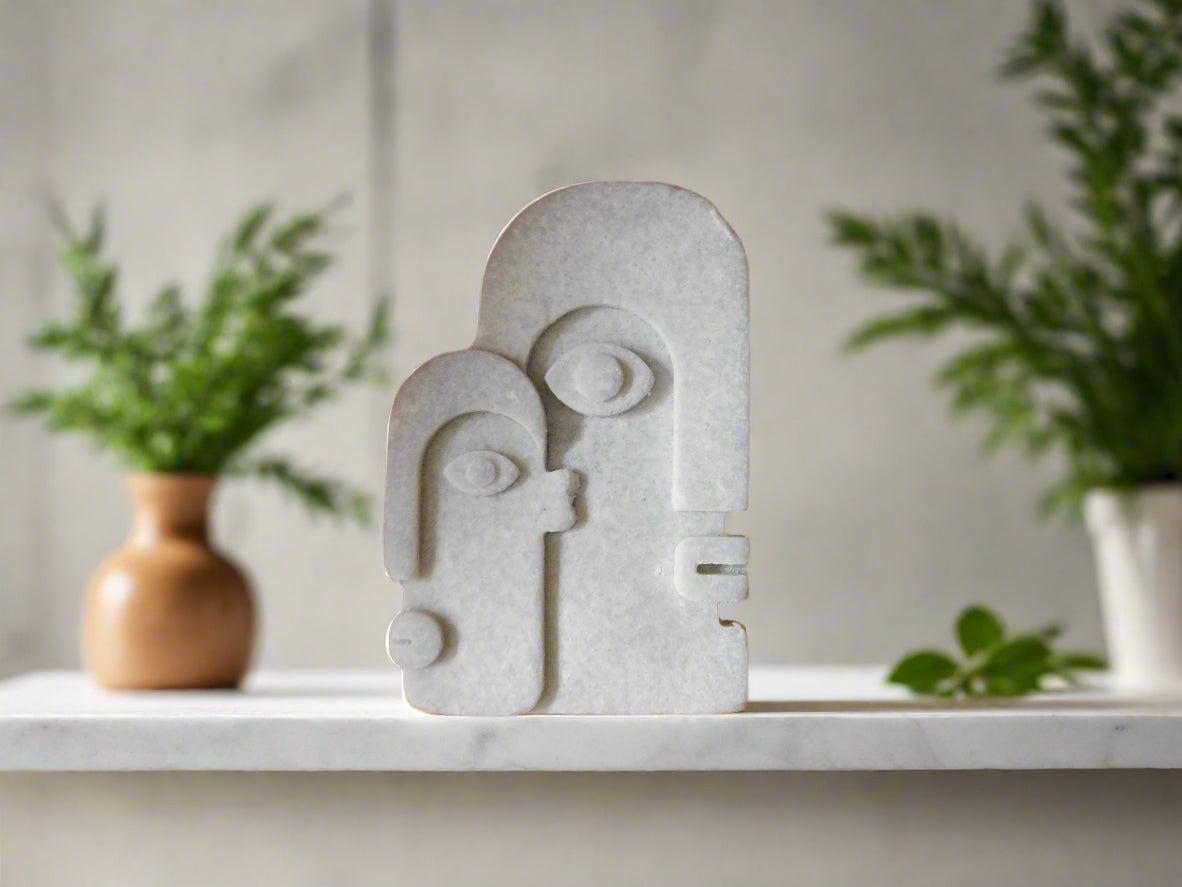 A bar of soap with a geometric face design on a shelf with plants in the background.