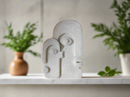A bar of soap with a geometric face design on a shelf with plants in the background.
