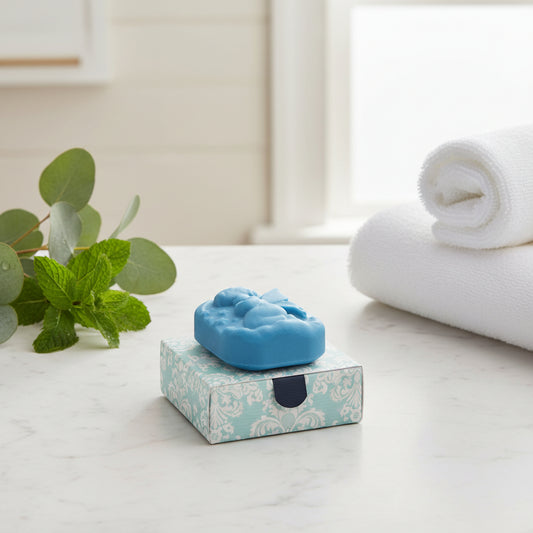 A dark green carved soap depicting a fairy, displayed on top of its patterned square box