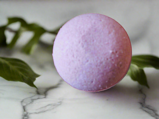 pink round bath bomb on the top a marble counter with leaves all around