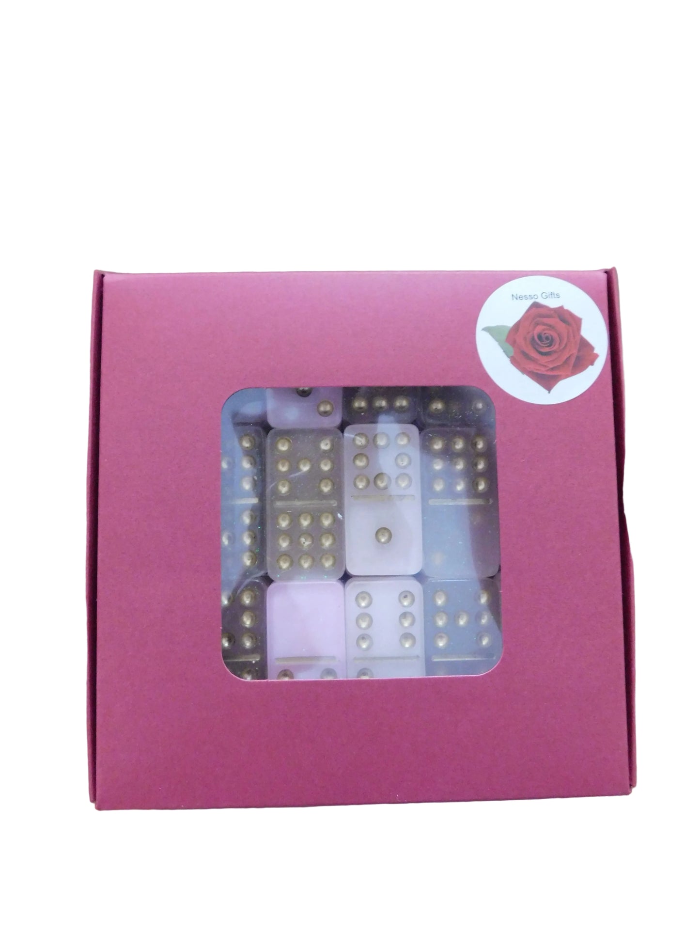 A red gift box with a clear window displaying pink and gold dominoes inside, set. A circular sticker with a red rose logo is visible on the top right corner of the box.