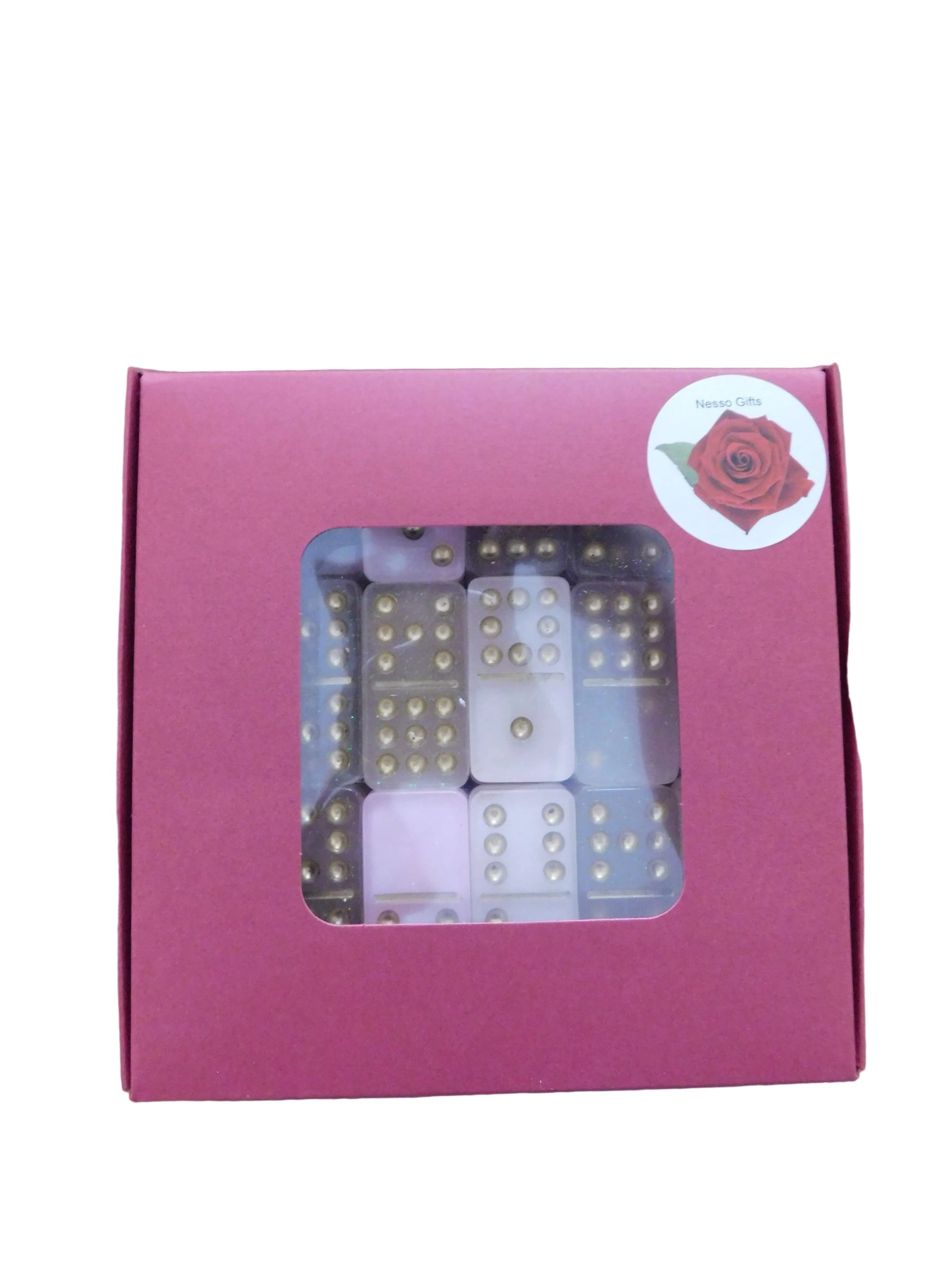 A red gift box with a clear window displaying pink and gold dominoes inside, set. A circular sticker with a red rose logo is visible on the top right corner of the box.