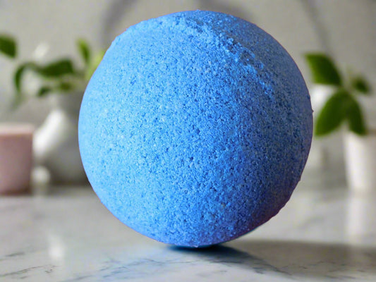 Snow bubble rounded blue bath bomb on the top of the counter on a back ground of plants 
