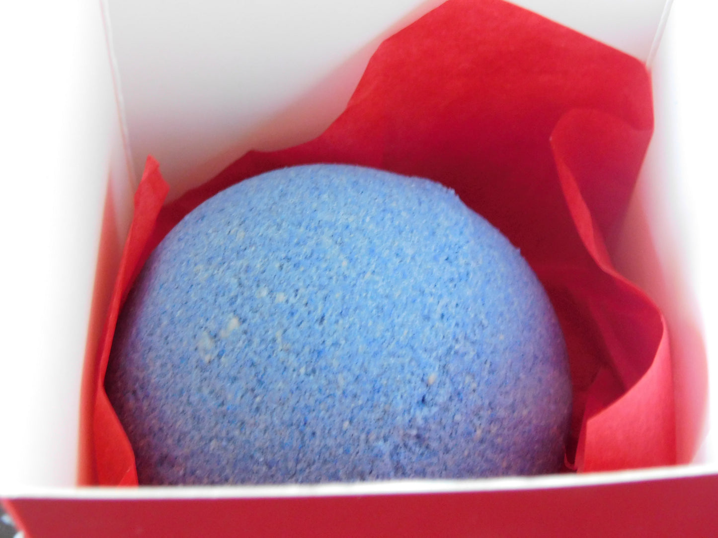 Blue bath bomb in a red box with white interior
