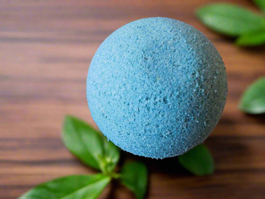 eucalyptus and mint green bath bomb ball on the top a wood surfice wth mint leaves all around
