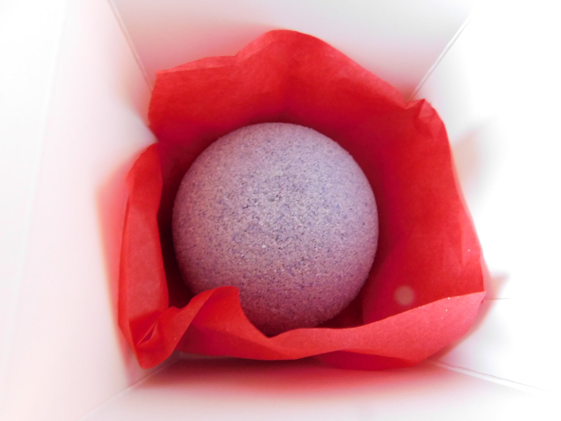 Purple bath bomb in a red box on a white background