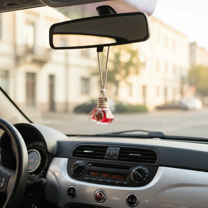 A small red glass bottle with a white string loop and a round paper tag, containing diffuser fragrance liquid.